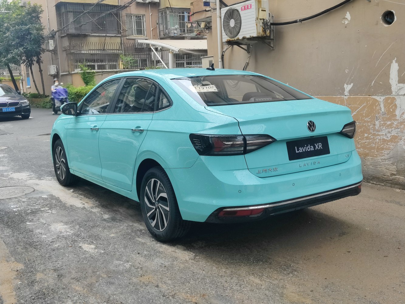 Bright blue sedan rear side view with modern taillights and alloy wheels