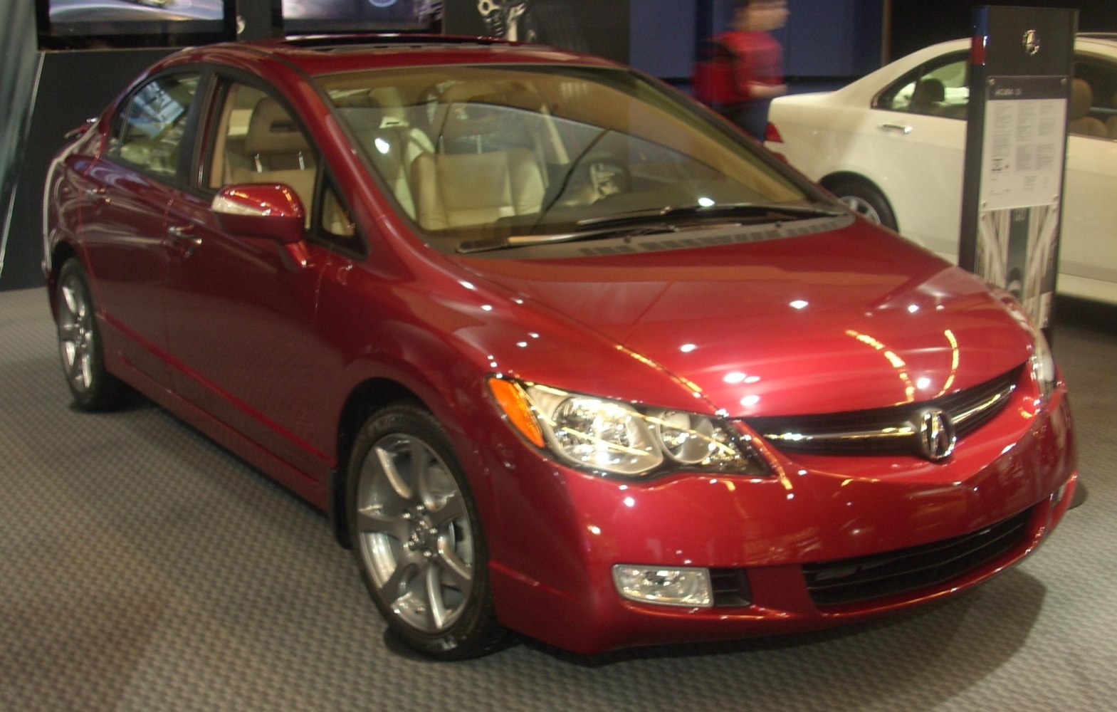 Red sedan with sleek headlights and alloy wheels