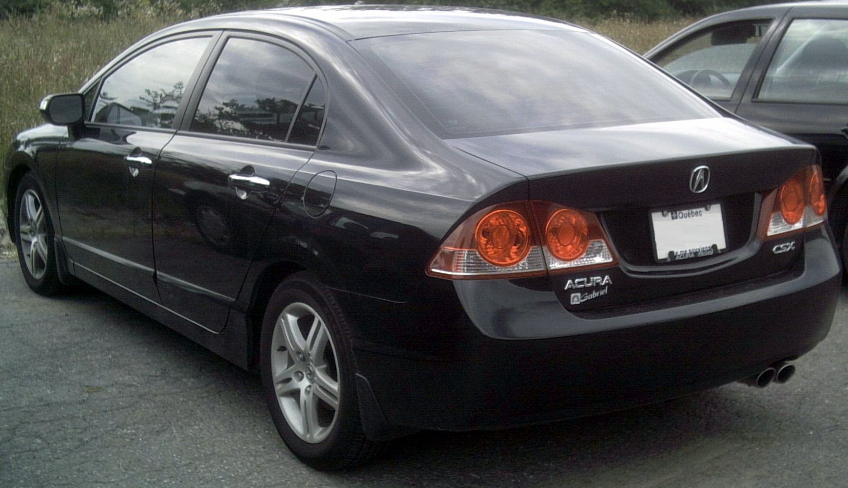 Rear and side view of a sedan with tinted windows and dual exhaust