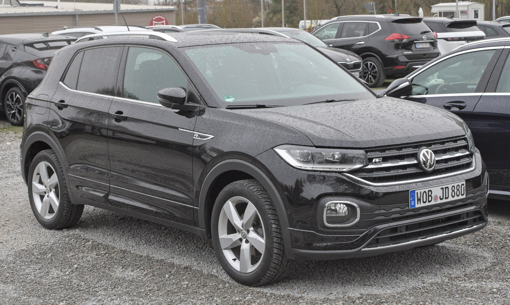 Compact SUV front angle with LED headlights and chrome grille in black, wet surface