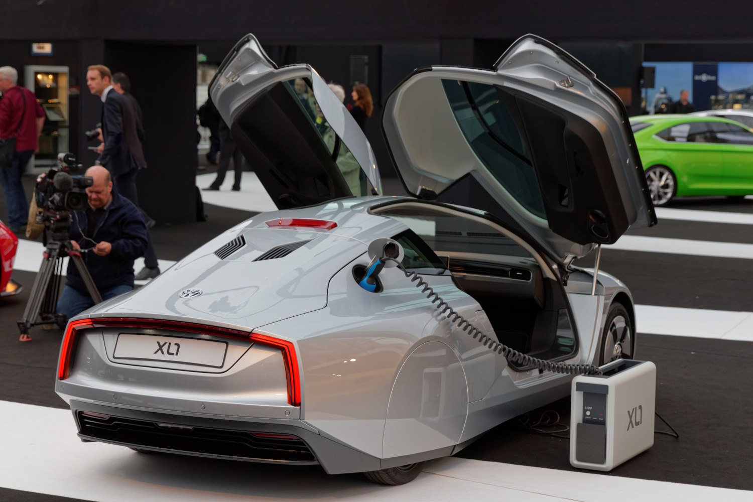 Electric car with gullwing doors charging at a station