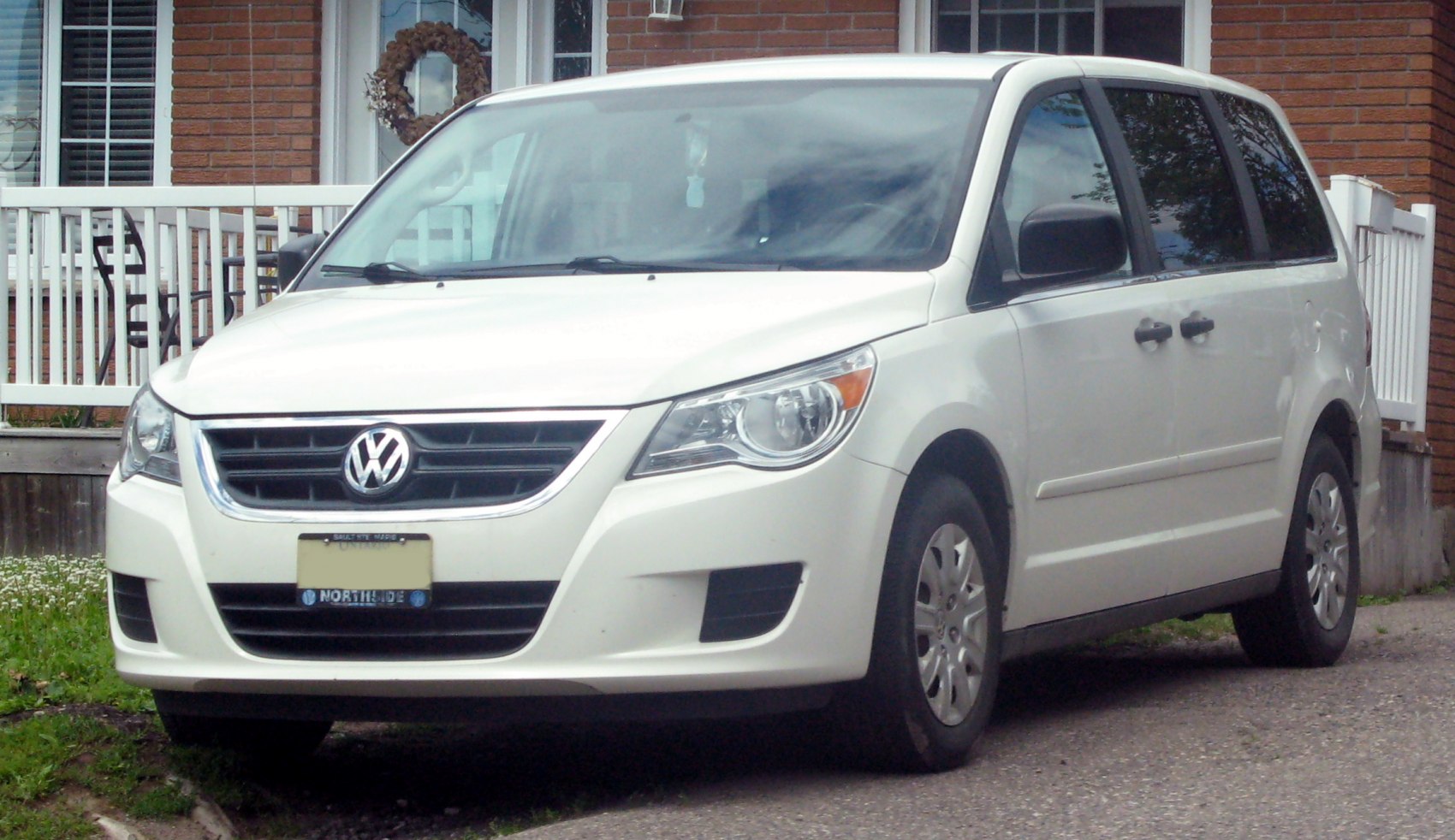 Front three-quarter view of a white minivan with sliding doors and detailed headlight design