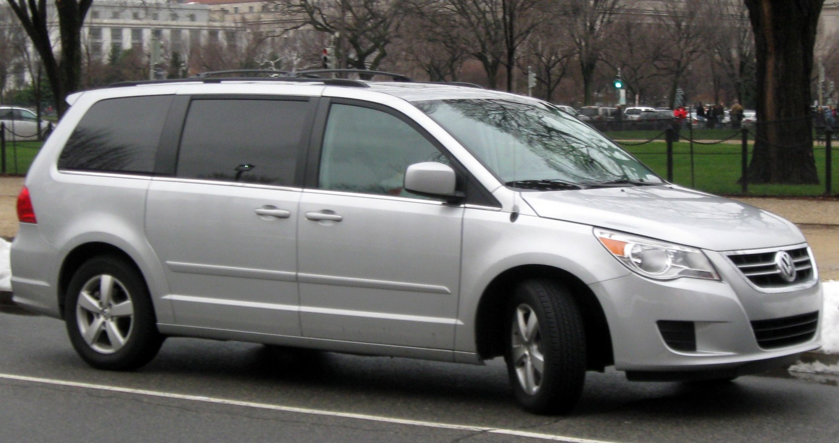 Silver minivan side profile with tinted windows and roof rack