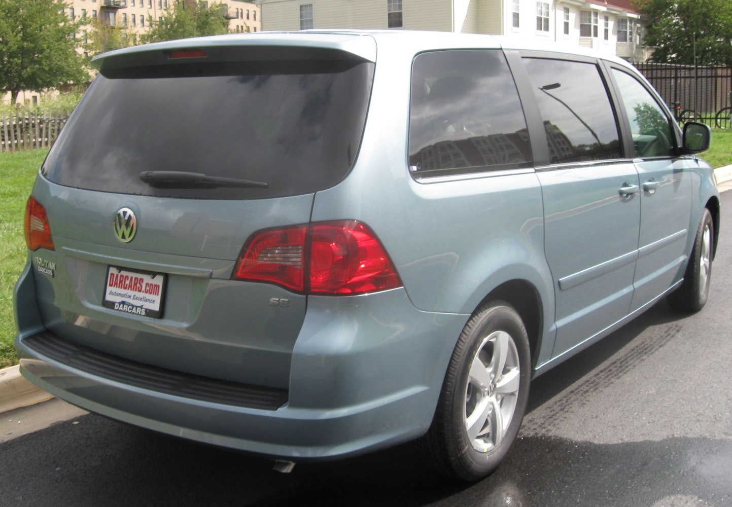 Rear side view of minivan with tinted windows and red tail lights.