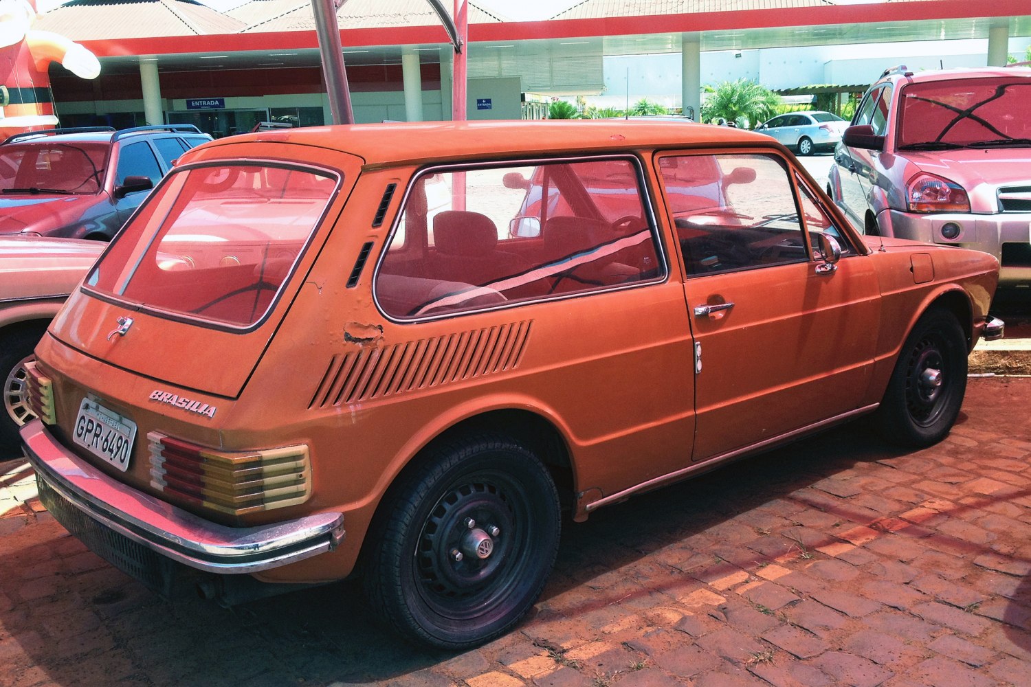 Orange 3-door hatchback with rear ventilation slats and angular vintage design.