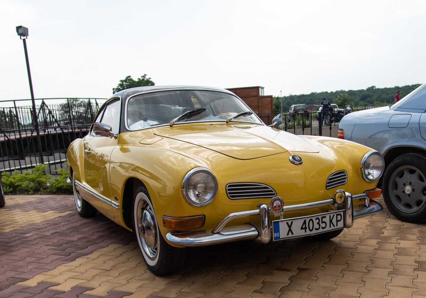 Yellow classic coupe front with round headlights, chrome bumper, and sleek curves