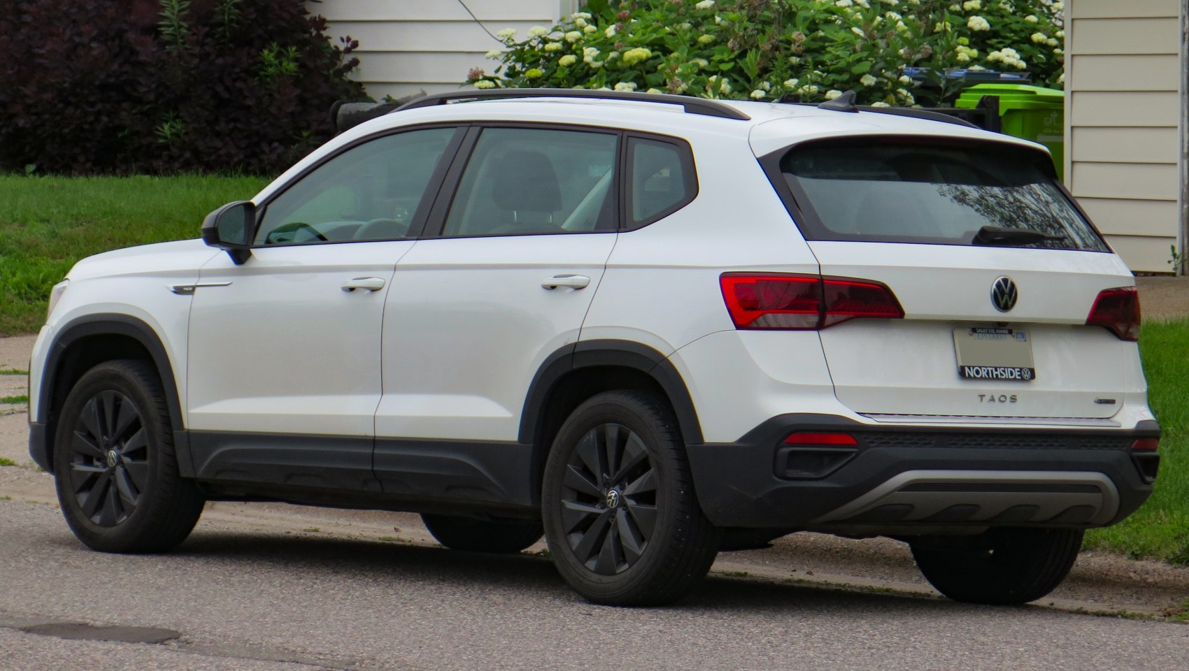 Rear and side view of a white compact SUV with black wheels and roof rails