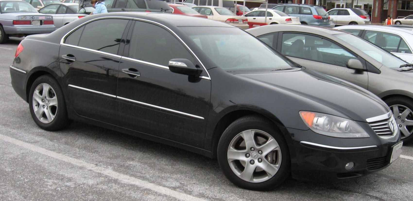 Front side view of black sedan with alloy wheels and chrome trim