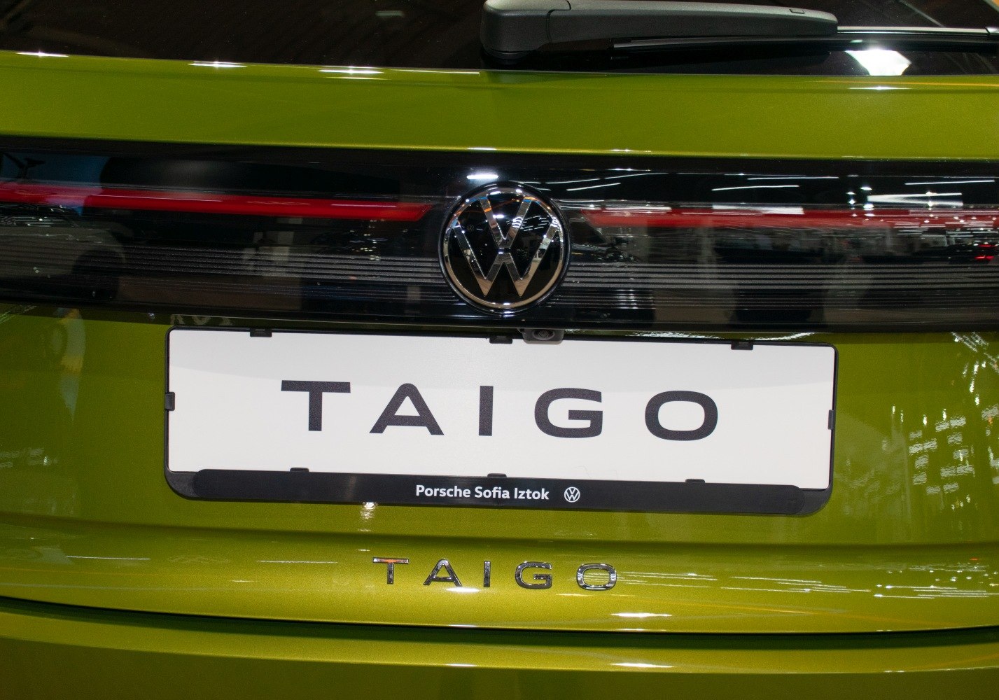 Close-up of rear VW logo and tail light strip on green vehicle
