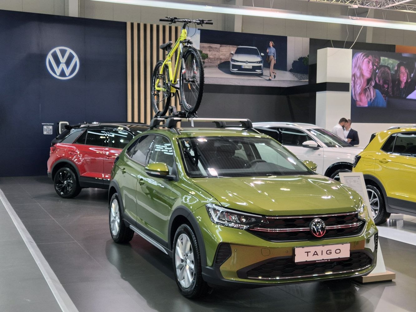 Green crossover SUV with roof-mounted bike carrier and bicycle.