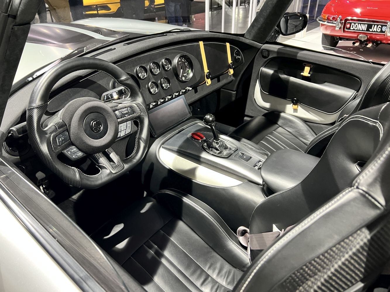 Carbon fiber dashboard with analog gauges and manual gearshift in a sports car interior