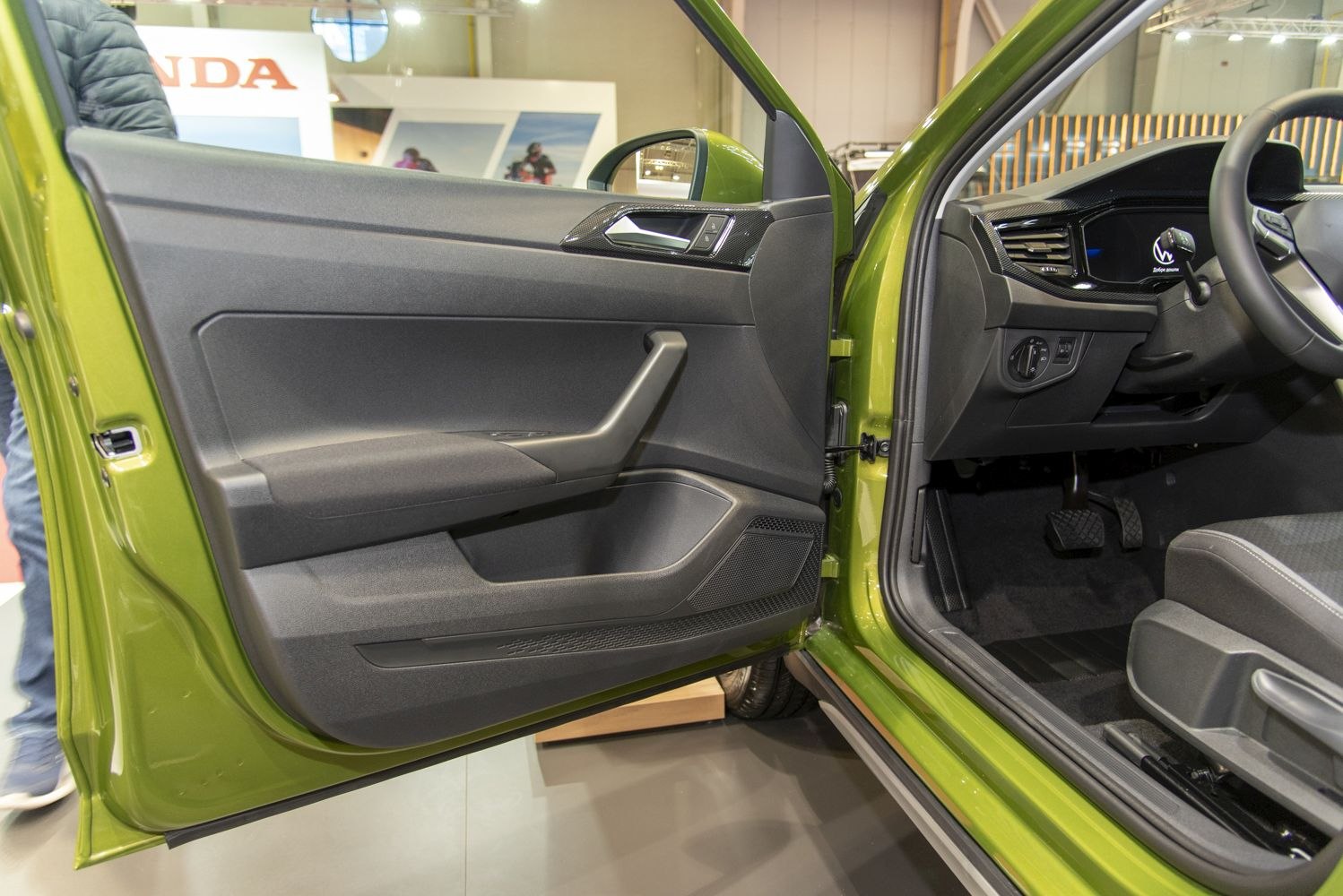 Driver side interior door panel and dashboard area with controls and seating.
