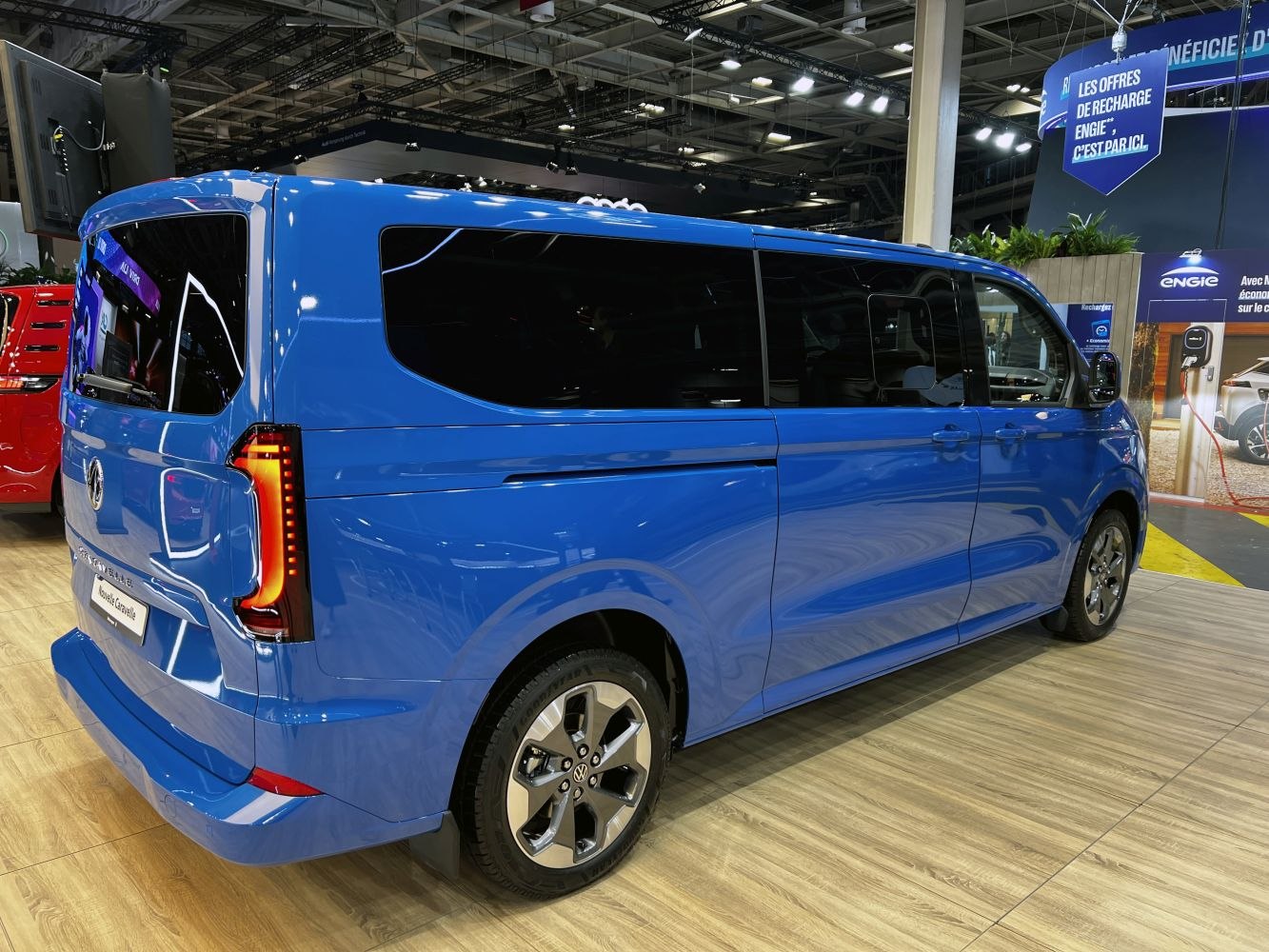 Modern blue passenger van with large windows and distinctive LED tail lights