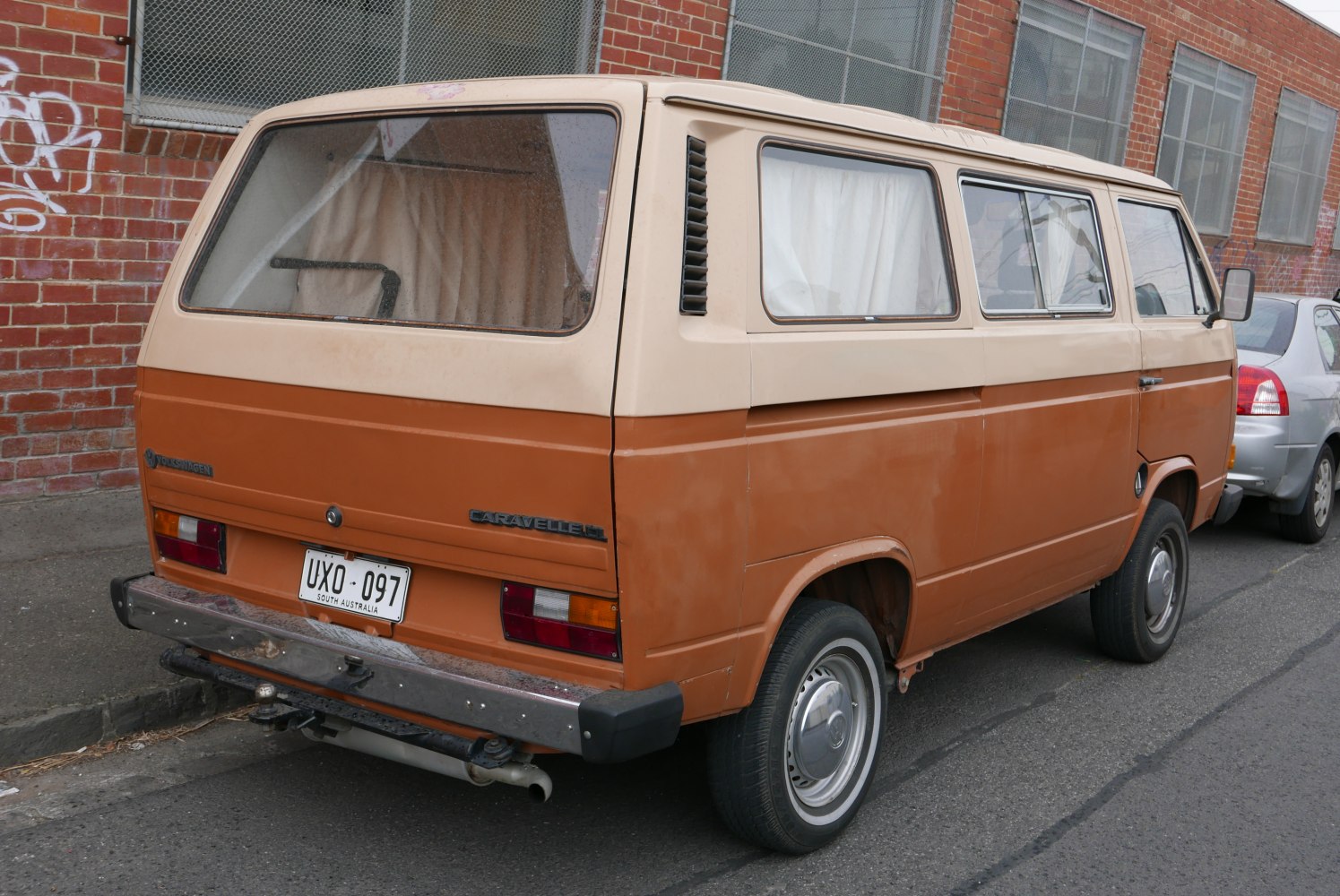 Vintage rear-view of a dual-tone boxy van with classic taillights and curtains
