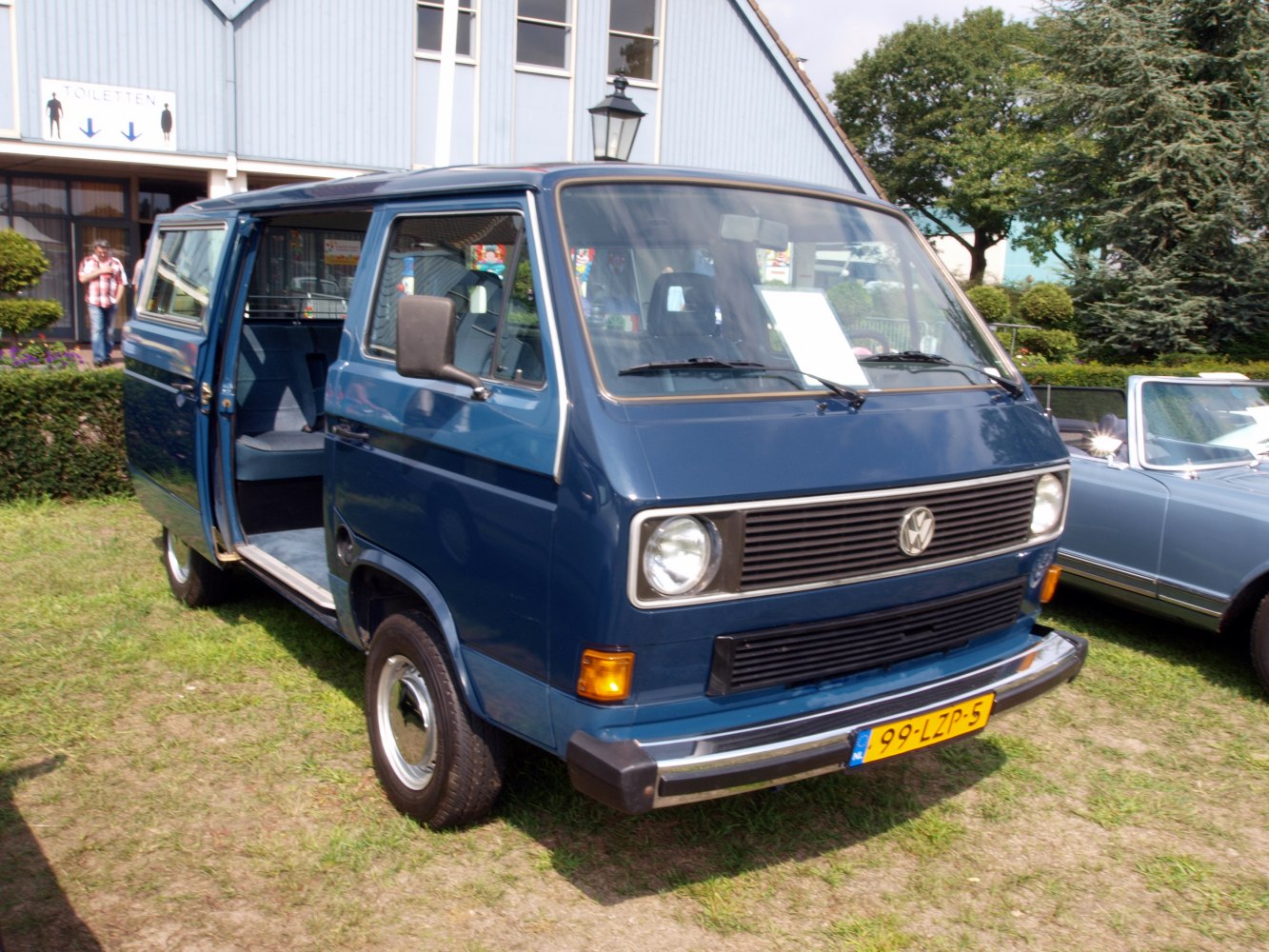 Blue vintage van with front sliding door open and rectangular headlights