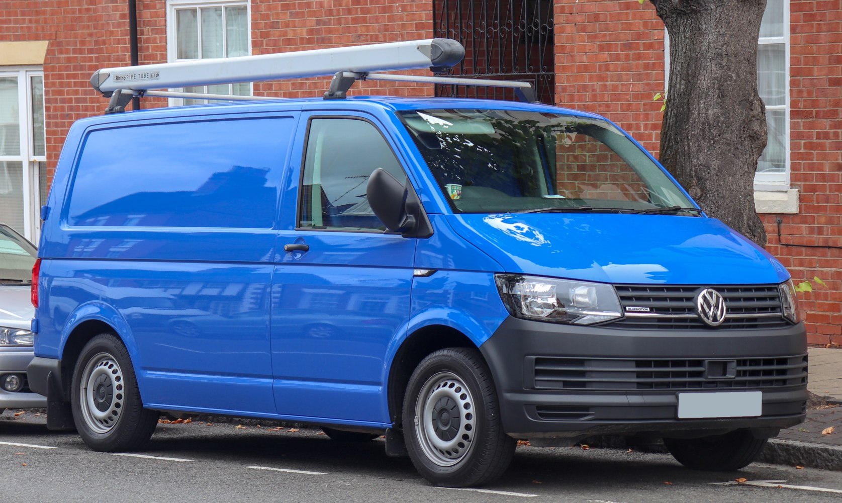 Blue panel van with roof rack and steel wheels parked on street