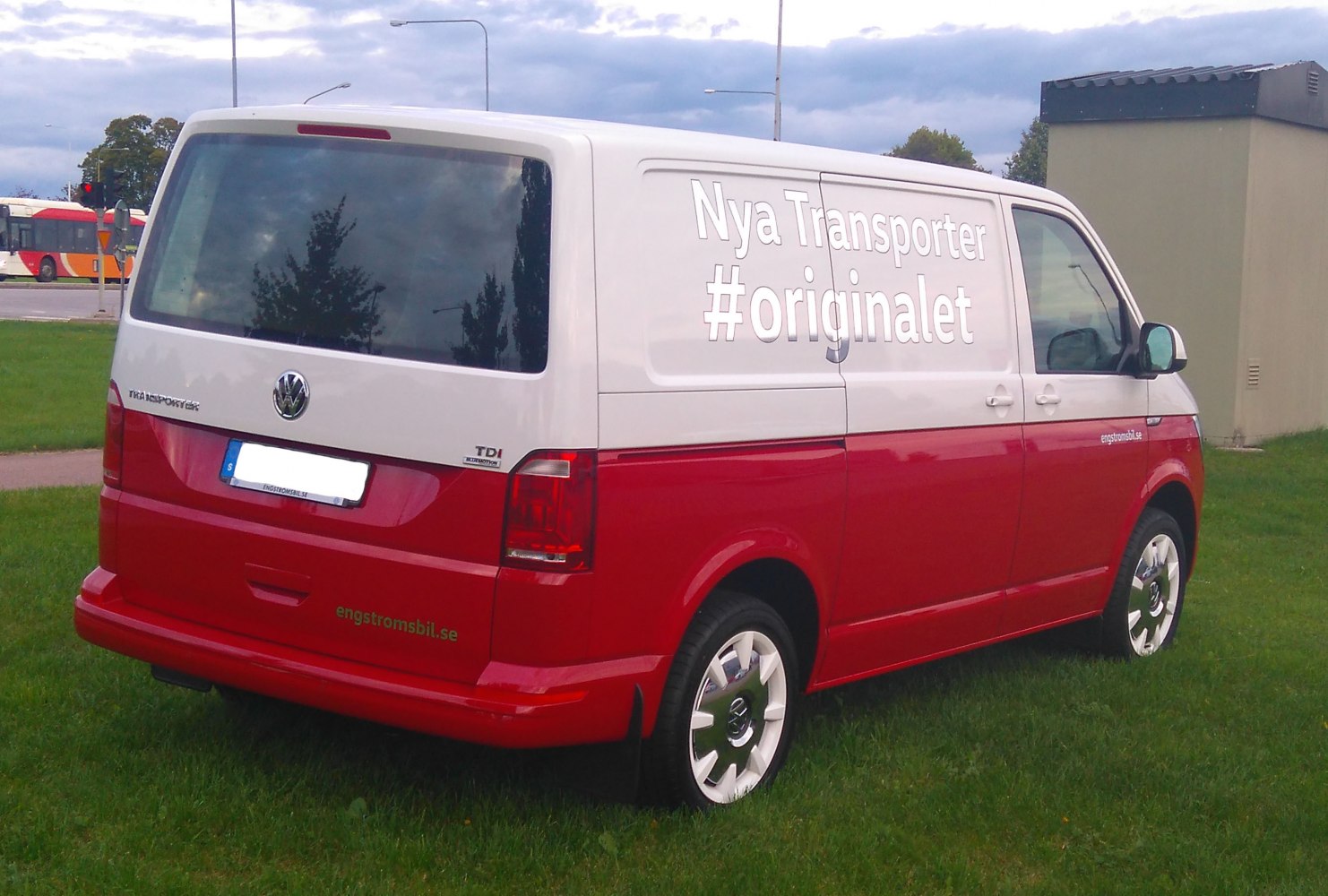 Two-tone panel van with rear window, alloy wheels, and side promotional text