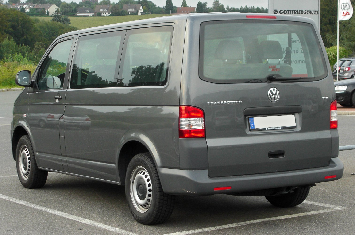 Rear and side view of gray van with large windows and taillights