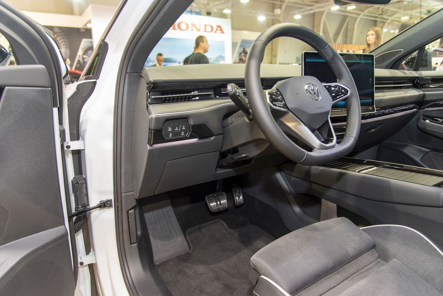 Modern steering wheel and digital dashboard with pedals and control buttons.