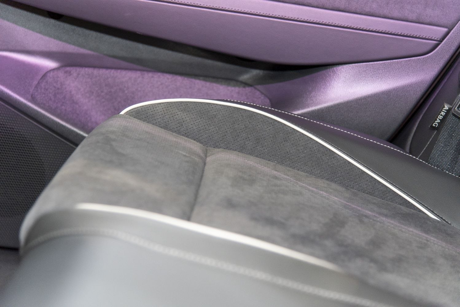 Close-up of car seat upholstery with contrasting piping and textured door panel.