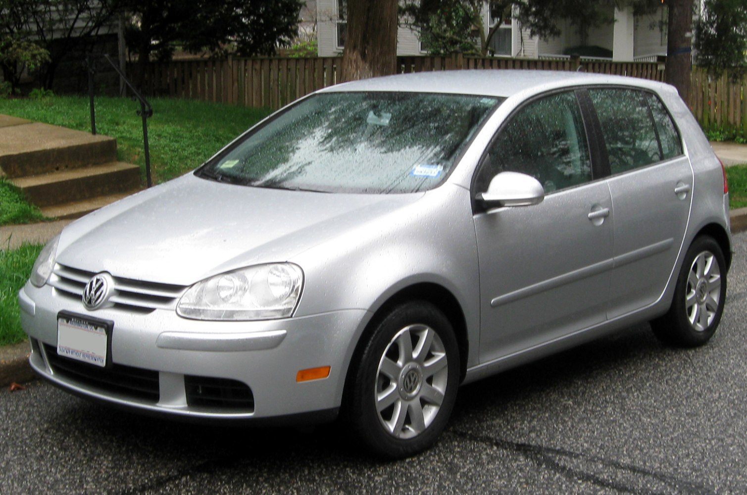 Silver 5-door hatchback with front-side park view in rain.