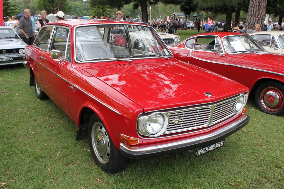 Red vintage sedan with chrome grille and round headlights on display