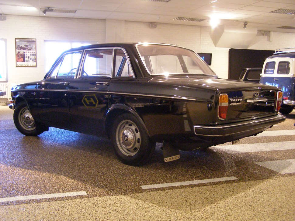 Rear and side view of a vintage black sedan with classic steel wheels and taillights.