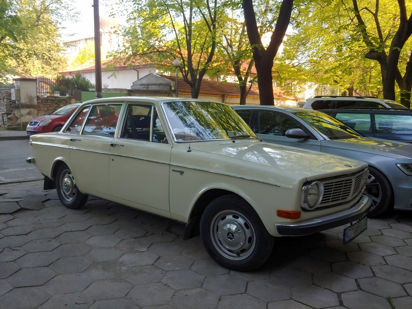 Vintage sedan with chrome rims and detailed front grille parked in shaded street