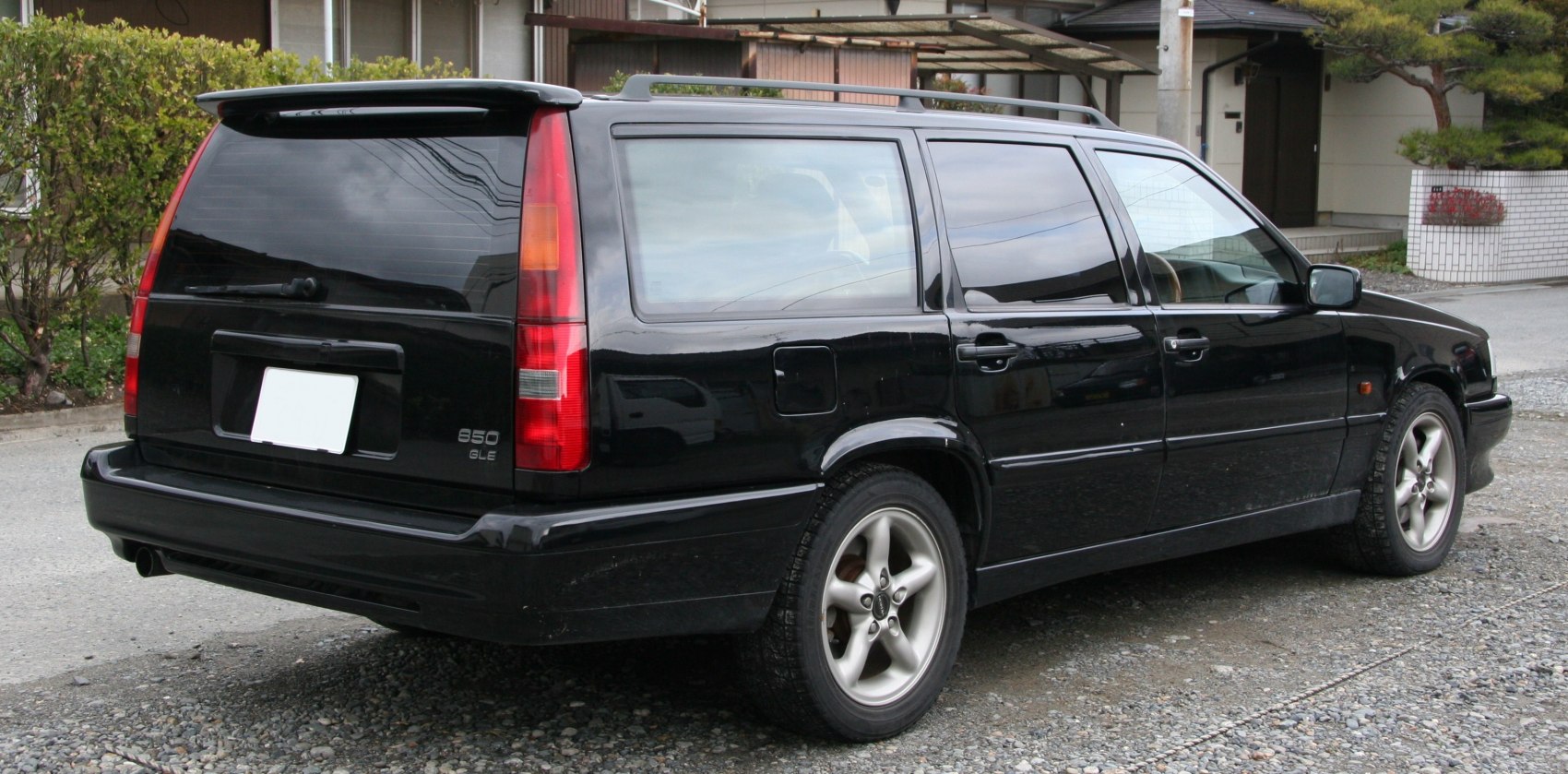 Rear side view of black station wagon with vertical taillights and alloy wheels.
