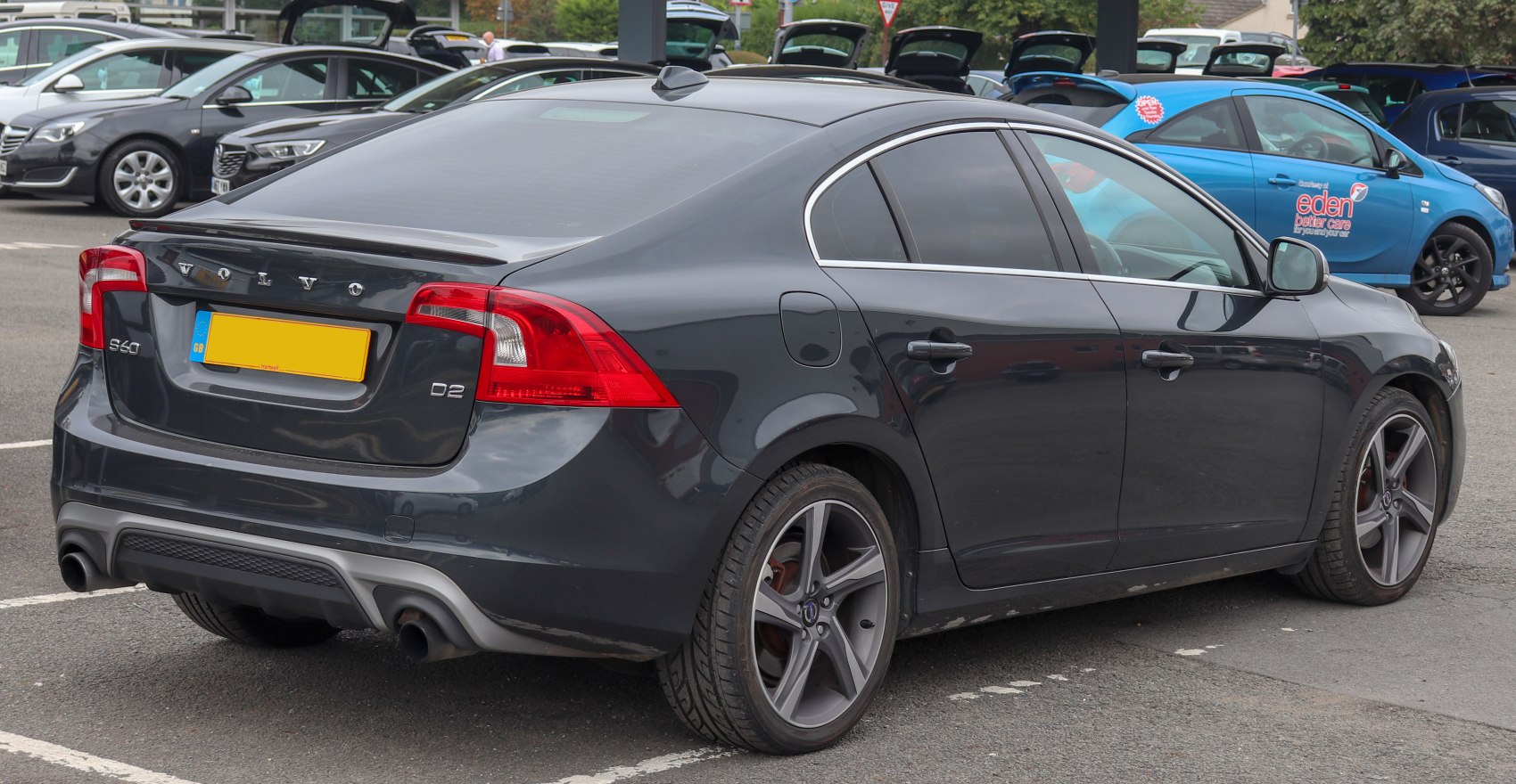 Rear view of a dark sedan with dual exhaust and distinctive taillights