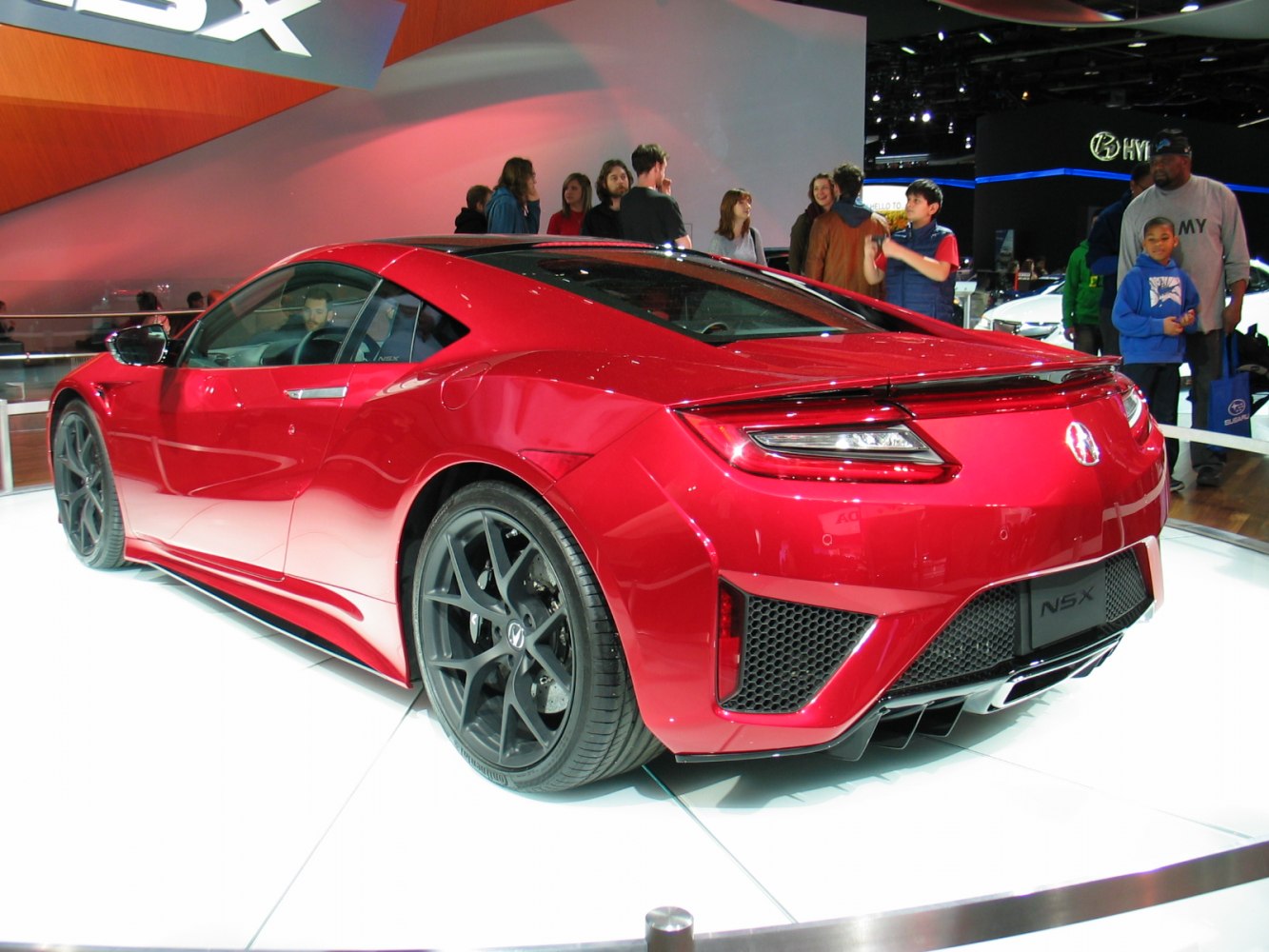 Red sports coupe rear side with black multi-spoke wheels and diffuser
