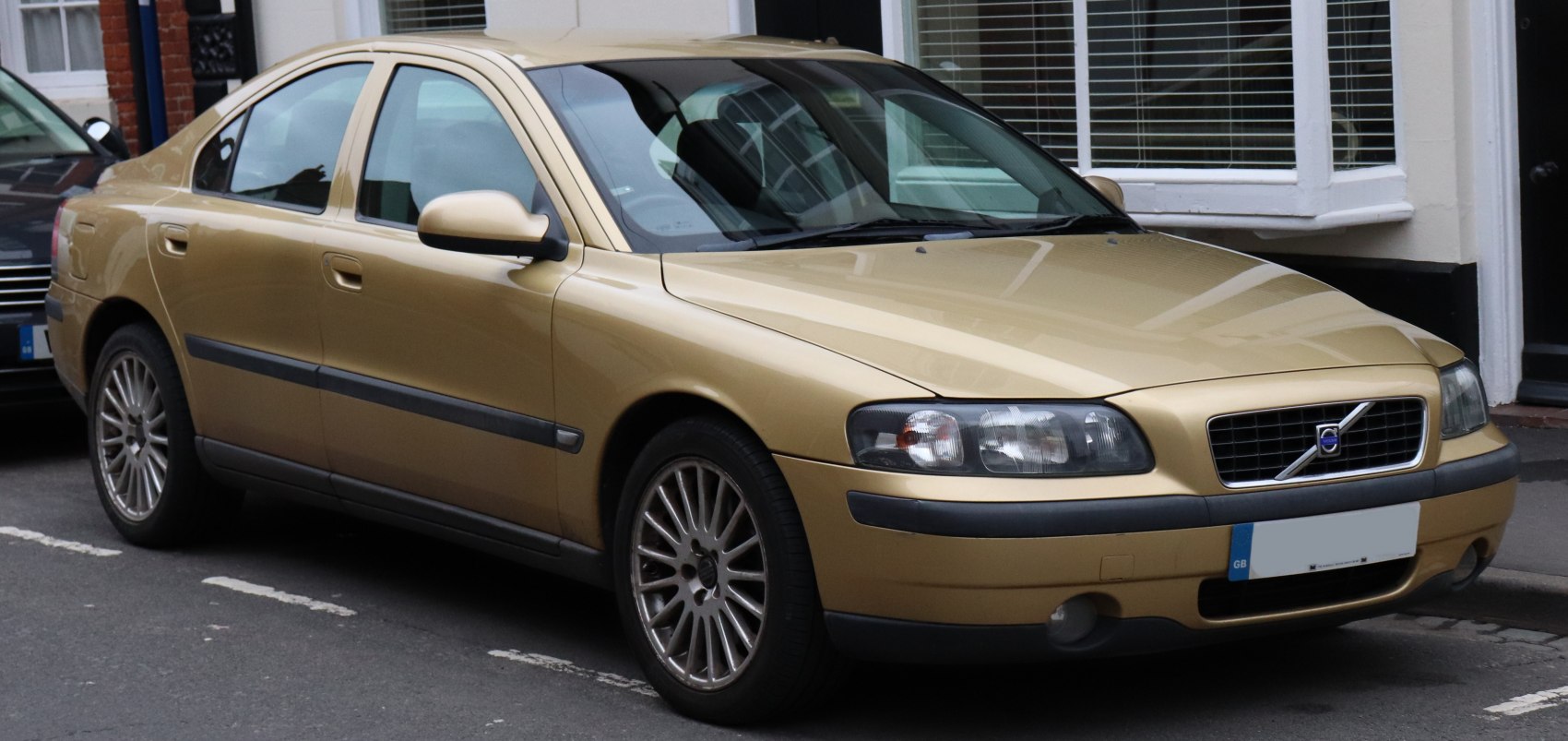 Front side view of beige sedan with alloy wheels and clear headlights