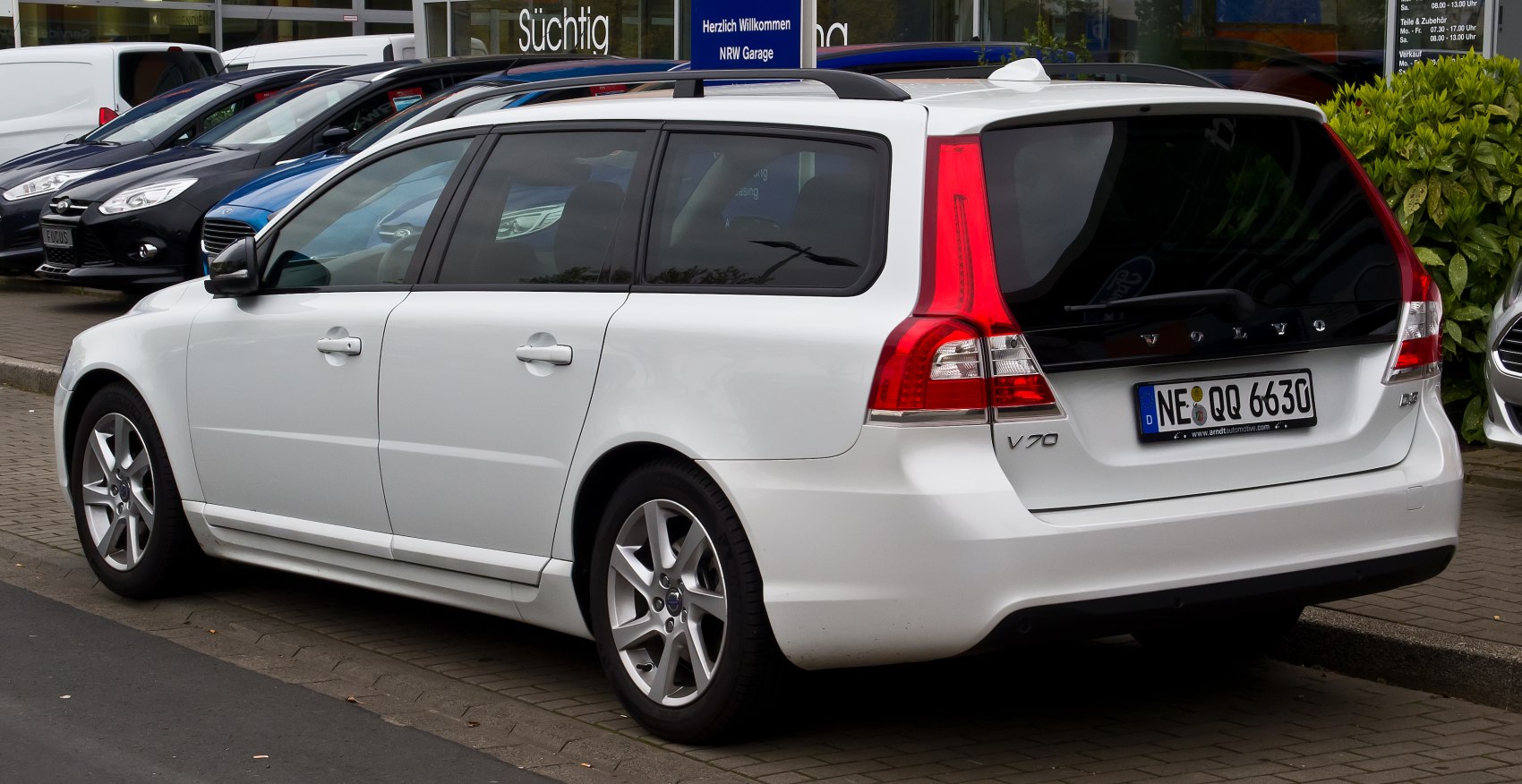 Rear side view of white station wagon with distinctive vertical taillights.