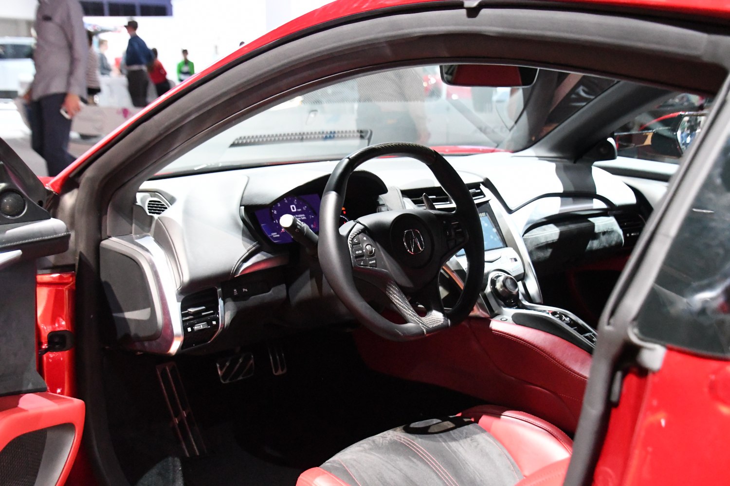 Steering wheel, digital instrument panel, red leather interior seating.