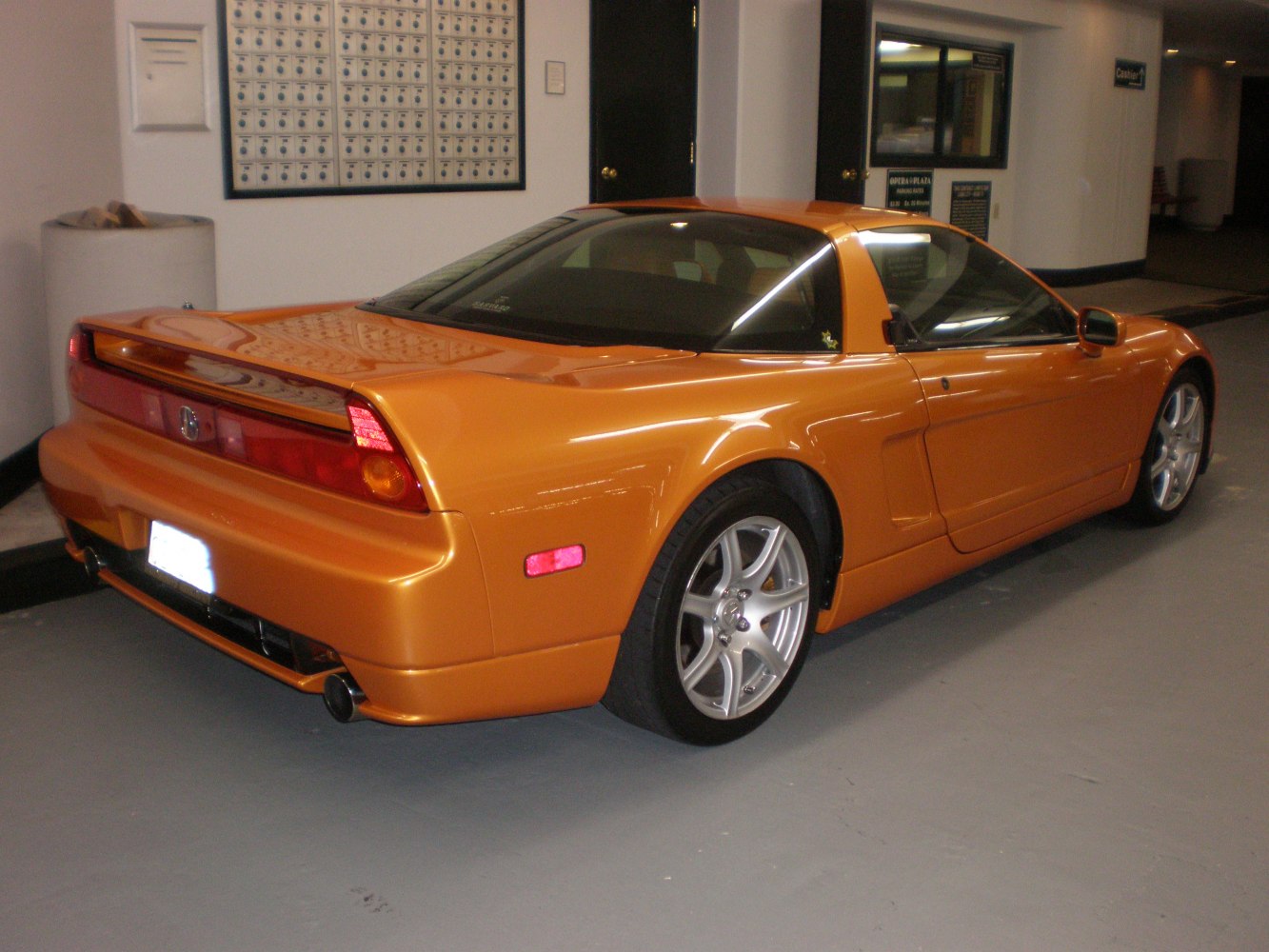Orange sports coupe rear side with distinctive tail lights and alloy wheels.