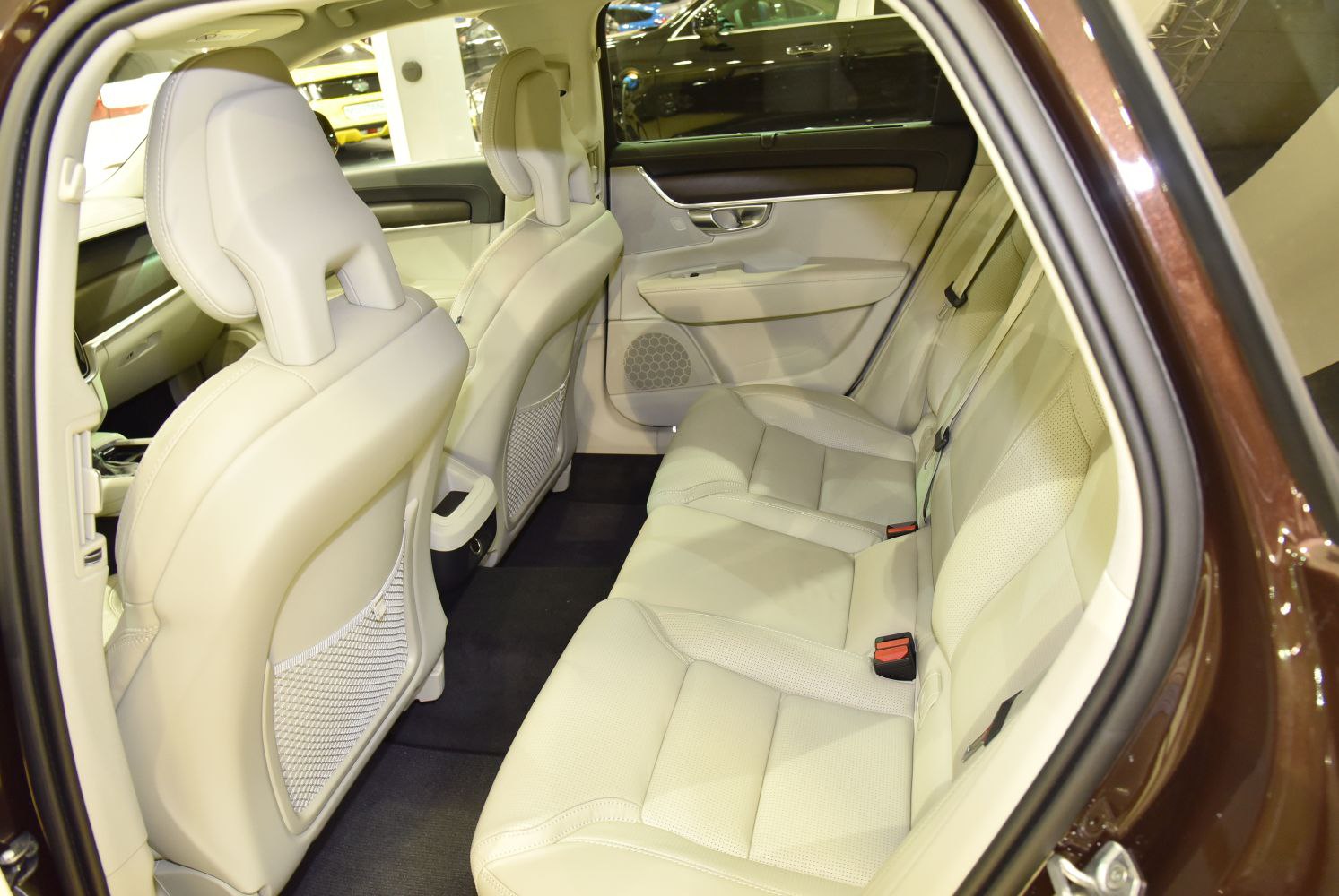 Spacious beige leather rear seat interior with door panel and seat belts