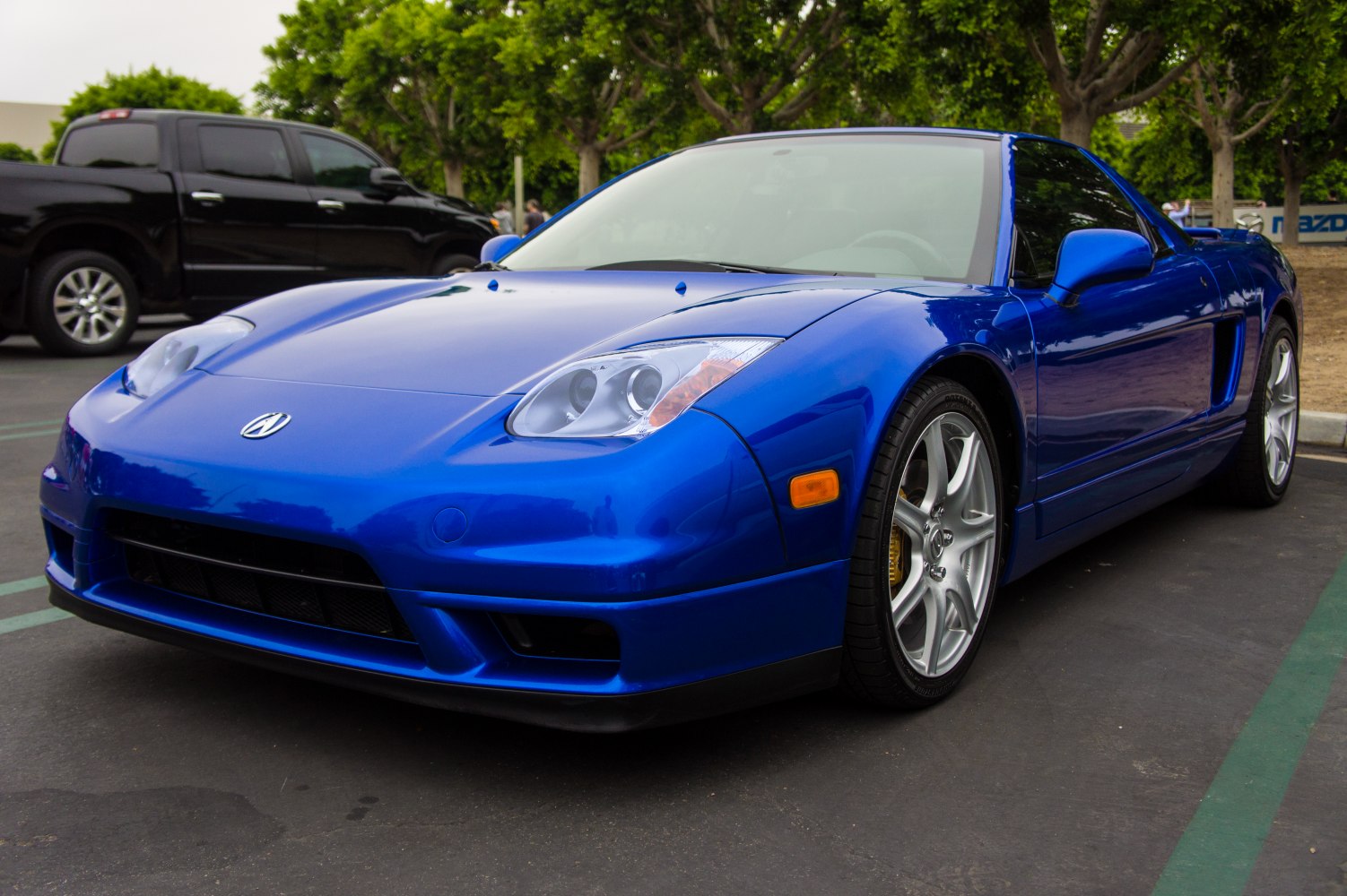 Blue sports car front side with alloy wheels.