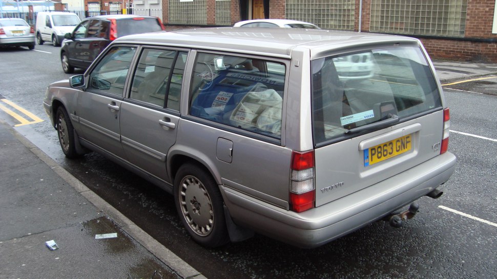 Rear-side view of a classic station wagon showing roof rails and tow hitch.
