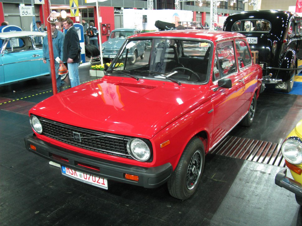 Red vintage compact 4-door sedan with black grille and round headlights.