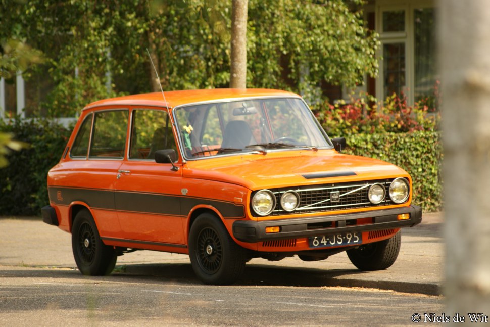 Orange vintage hatchback with round headlights and black side stripe