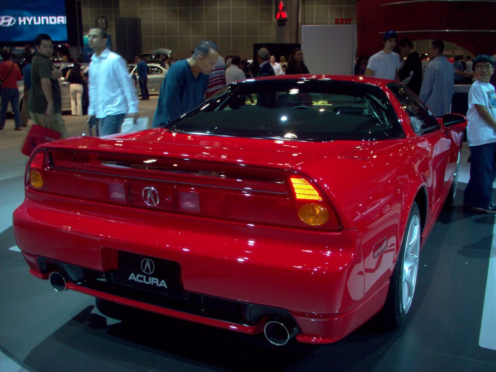 Red sports car rear with dual exhausts and distinctive taillights