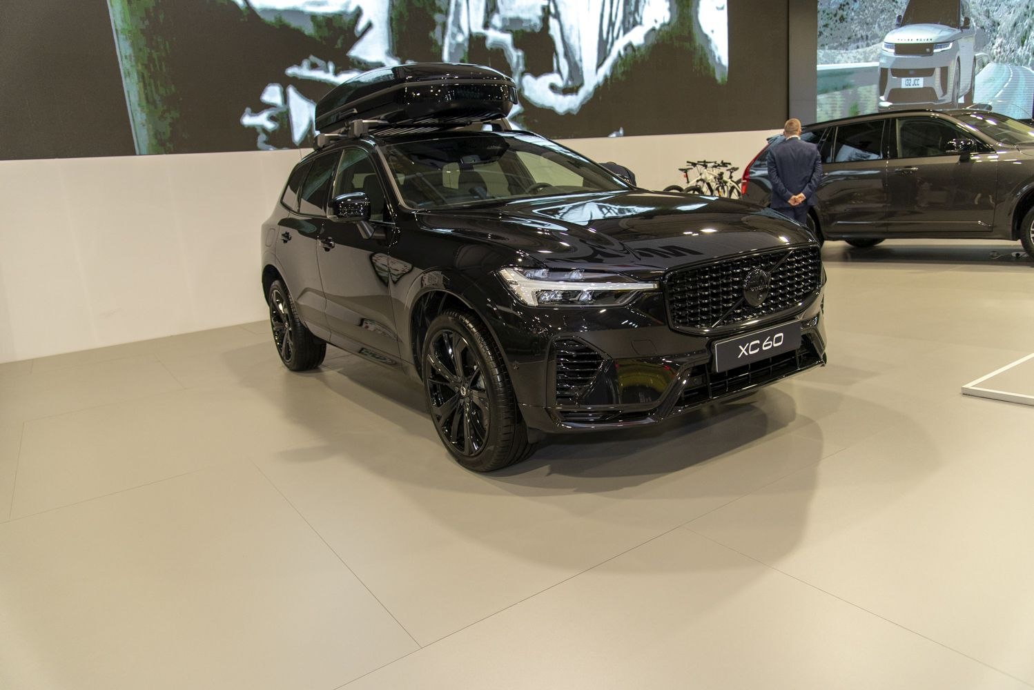 Black SUV with roof-mounted storage box in indoor exhibit