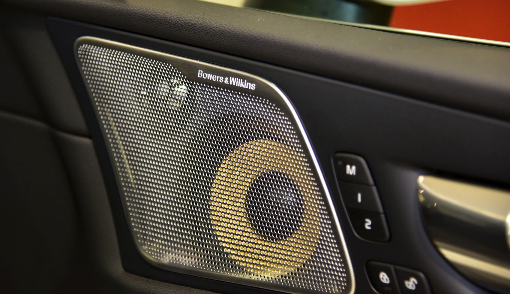 Close-up of premium car door speaker with memory seat buttons.
