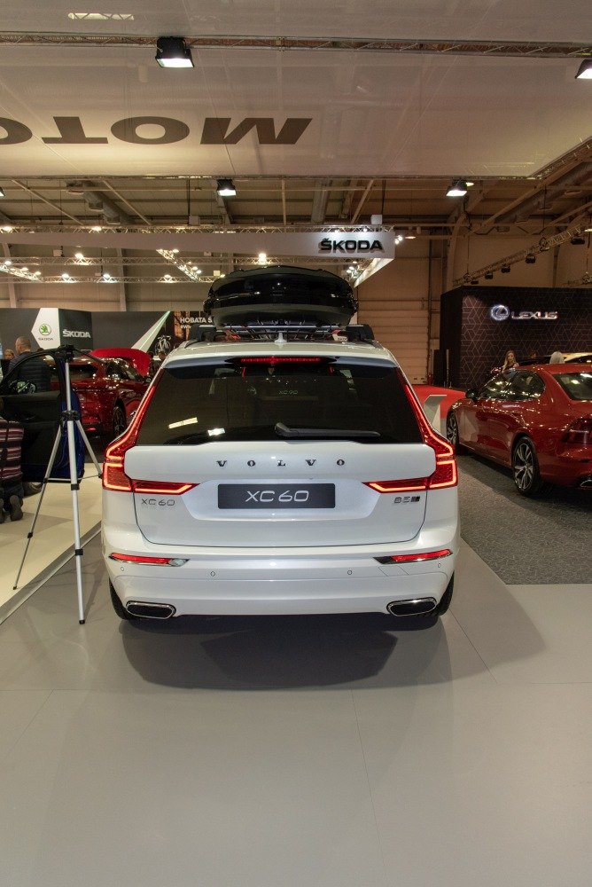 Rear view of a white SUV with distinctive taillights and roof cargo box.