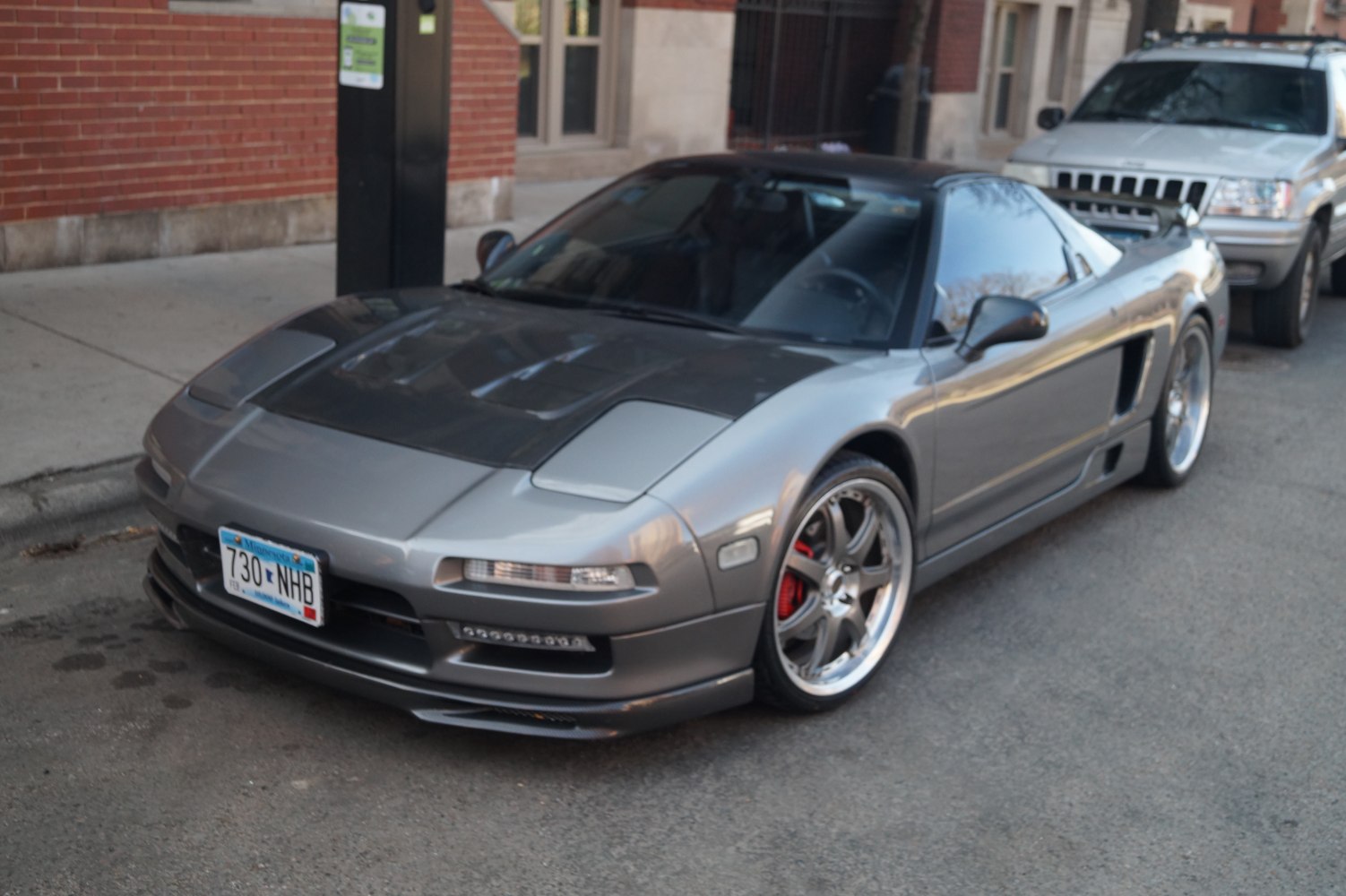 Custom alloy wheels and carbon fiber hood on a 1990s sports coupe