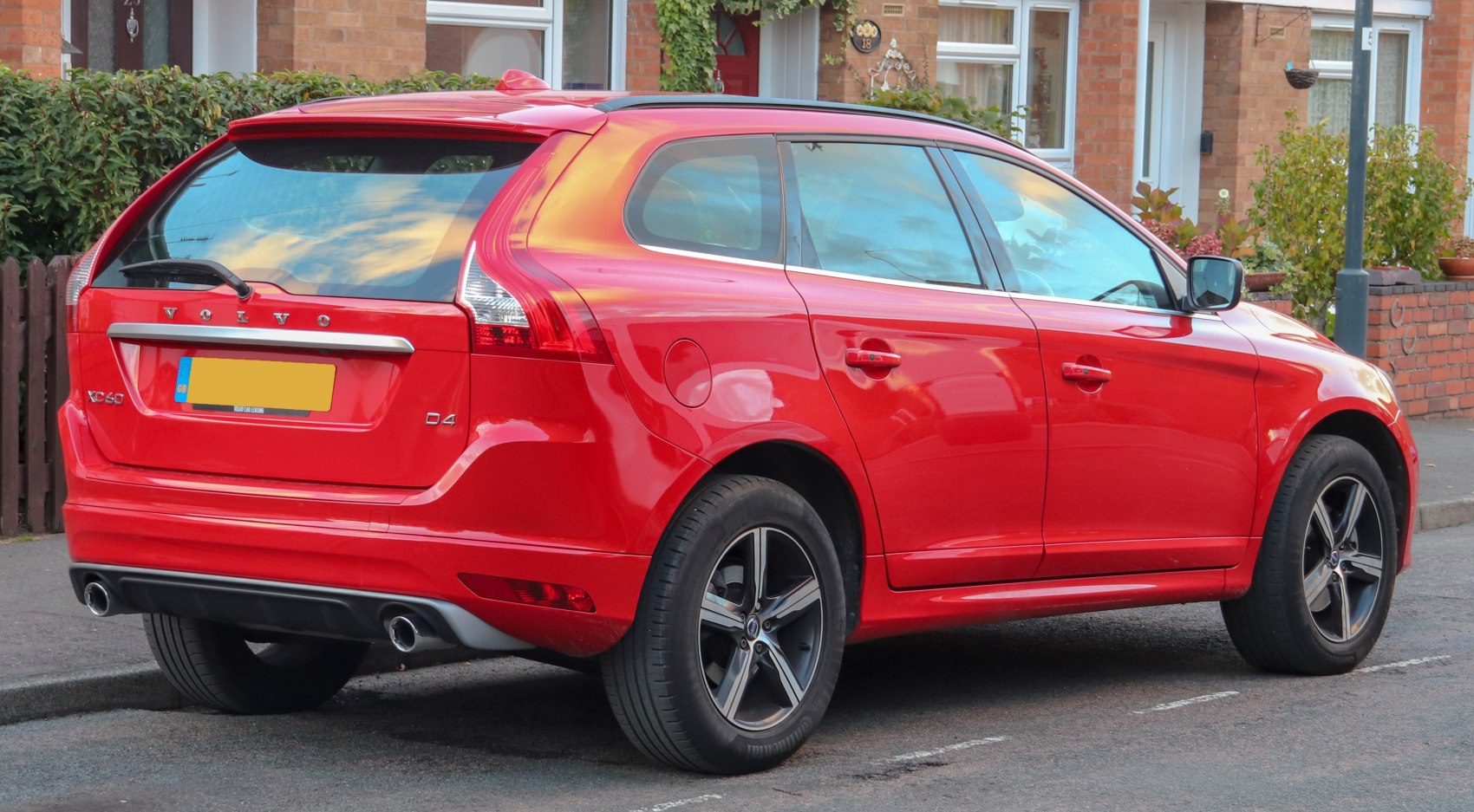 Rear side view showing dual exhaust, roof spoiler, alloy wheels on red SUV
