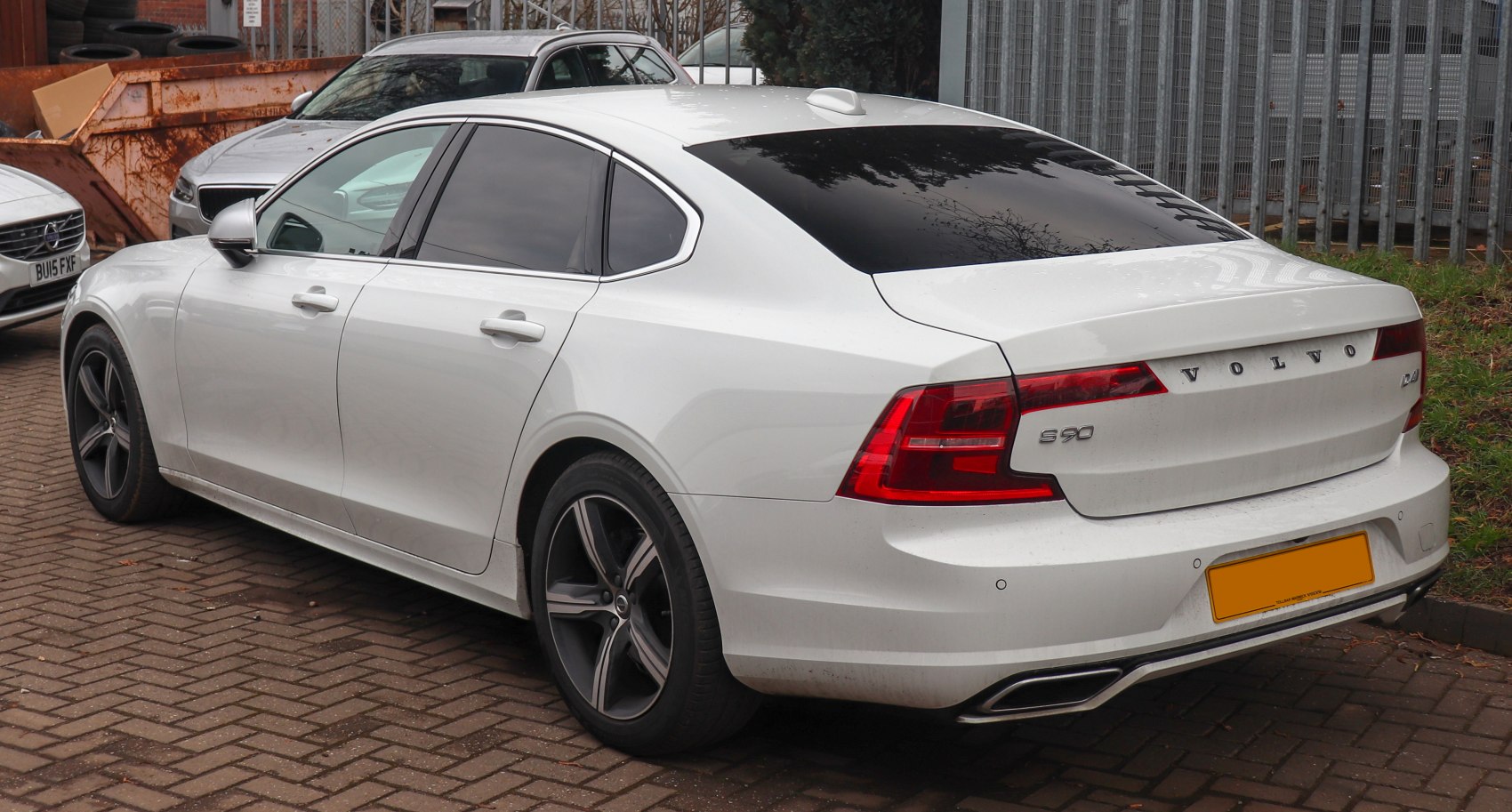 Rear side view of white sedan with distinctive tail lights and dual exhaust