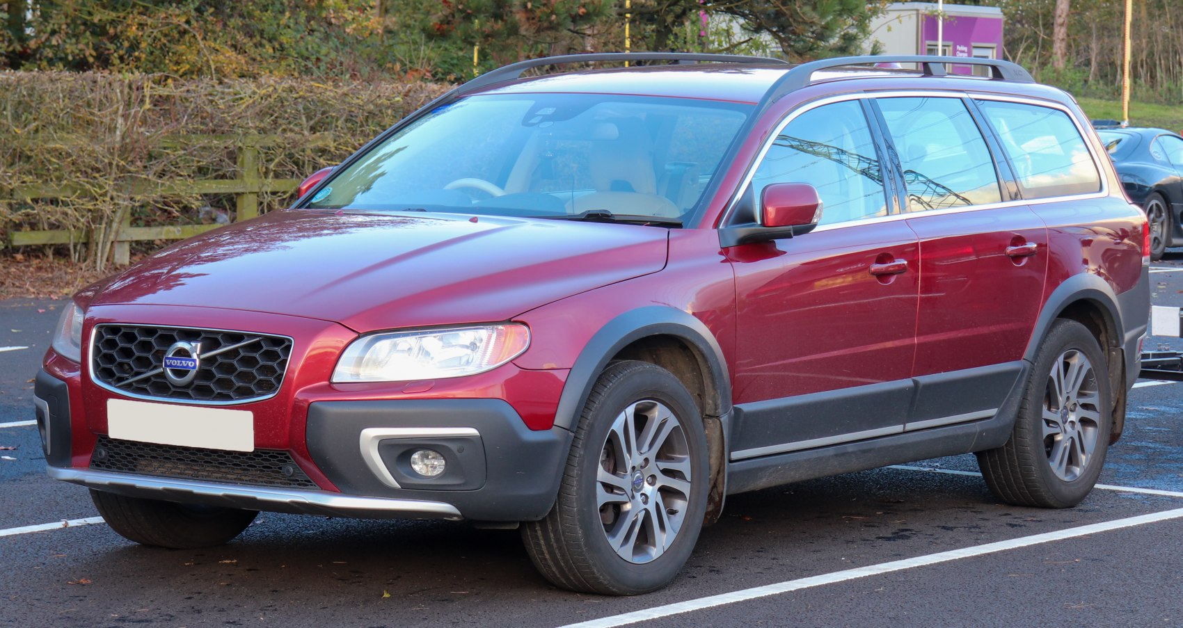Red SUV with rugged body cladding and roof rails in front side view