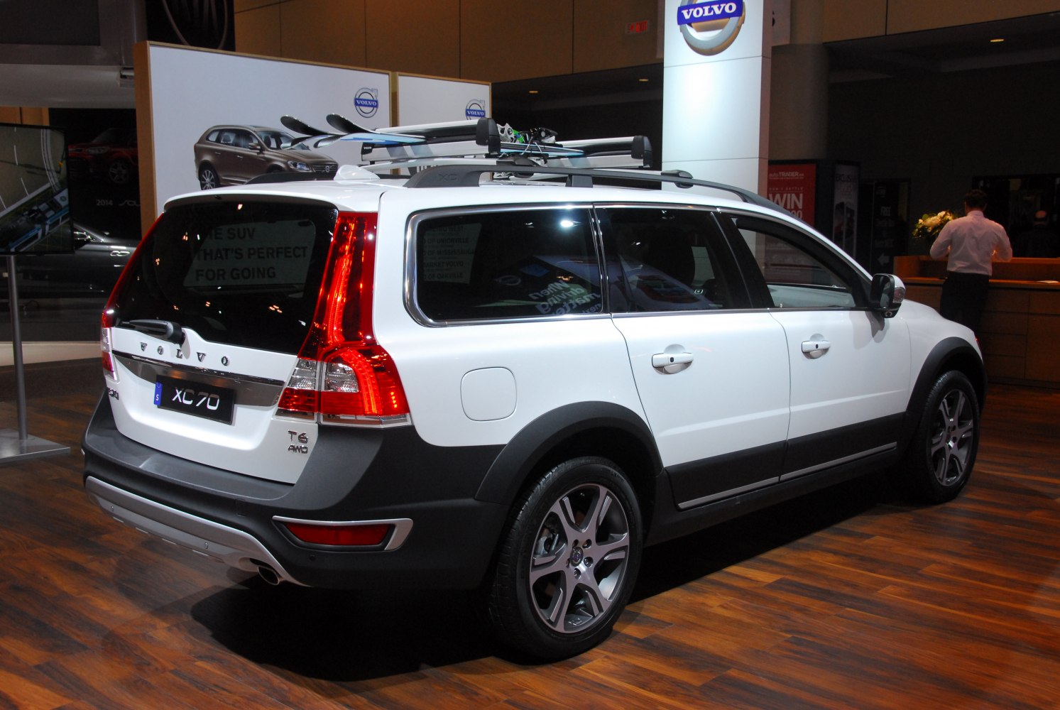Rear side view of a white station wagon with roof rack and skis