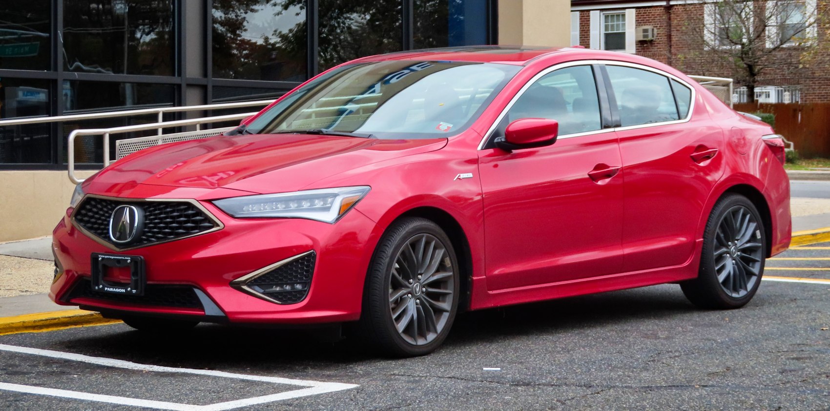 Front and side view of a red sporty sedan with updated grille and alloy wheels